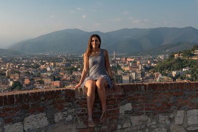 Full length of happy young woman against buildings in city