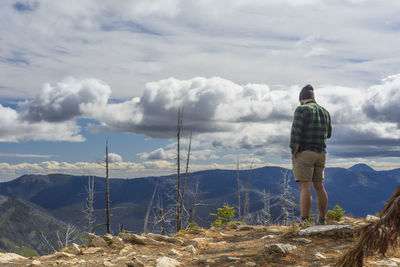 Male hiker standing on mountain top with dramatic clouds