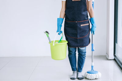 Low section of cleaner with mop and bucket standing on tiled floor