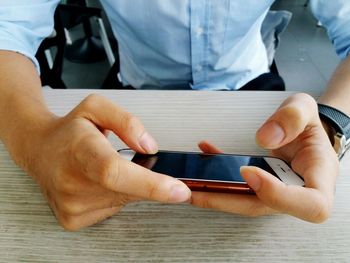 Midsection of man using mobile phone at table