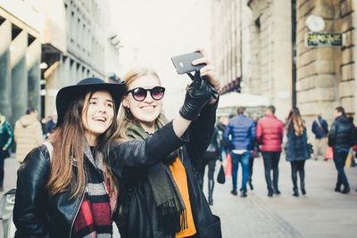Two women taking selfie with mobile phone in city