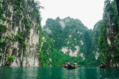 People on boat against trees and mountain range