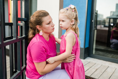 Portrait of mother and daughter sitting on railing