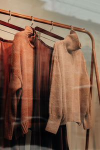 Silk brown long skirts and knitted sweaters hanging in a row in the window of a women's fashion