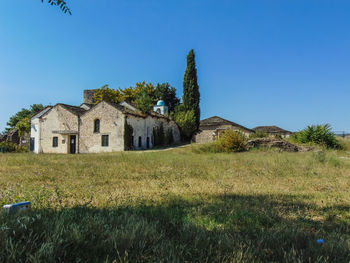 House on field against clear blue sky