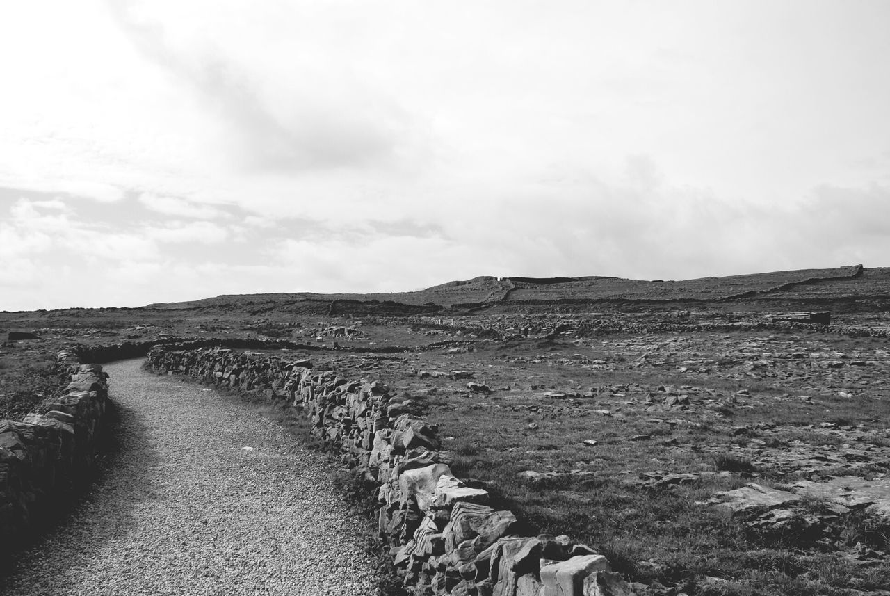 sky, the way forward, tranquil scene, tranquility, landscape, dirt road, road, scenics, nature, diminishing perspective, non-urban scene, beauty in nature, remote, day, cloud - sky, horizon over land, rock - object, sand, arid climate, desert