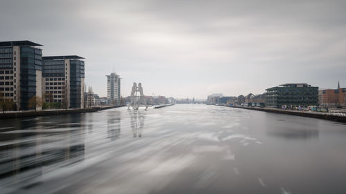 Modern cityscape by water against sky