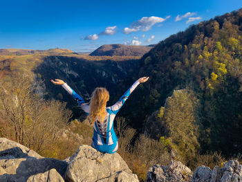 Rear view of woman sitting on rock