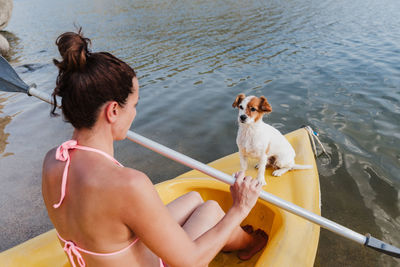 Smiling woman canoeing with dog in lake