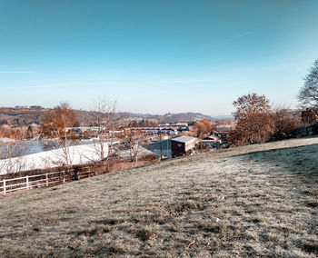 Houses on field by buildings against sky