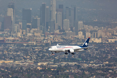 Airplane flying over city against sky