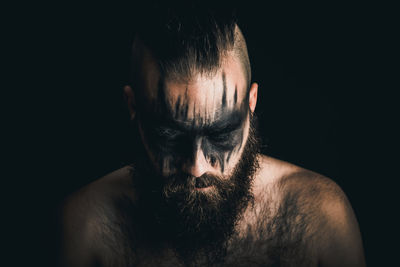 Portrait of shirtless man against black background