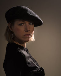 Close-up portrait of woman against beige wall