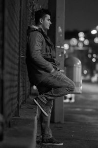 Side view of man leaning against wall