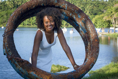 Portrait of young woman standing by lake