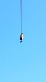 Low angle view of overhead cable car against clear blue sky