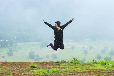 Rear view of young woman moving down on grassy hill