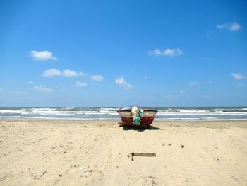 Deck chairs on beach against sky
