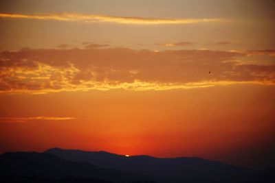 Scenic view of silhouette mountains against orange sky