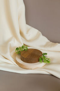 Empty wooden podium gray background. product presentation with flowers, silk cloth and leaves