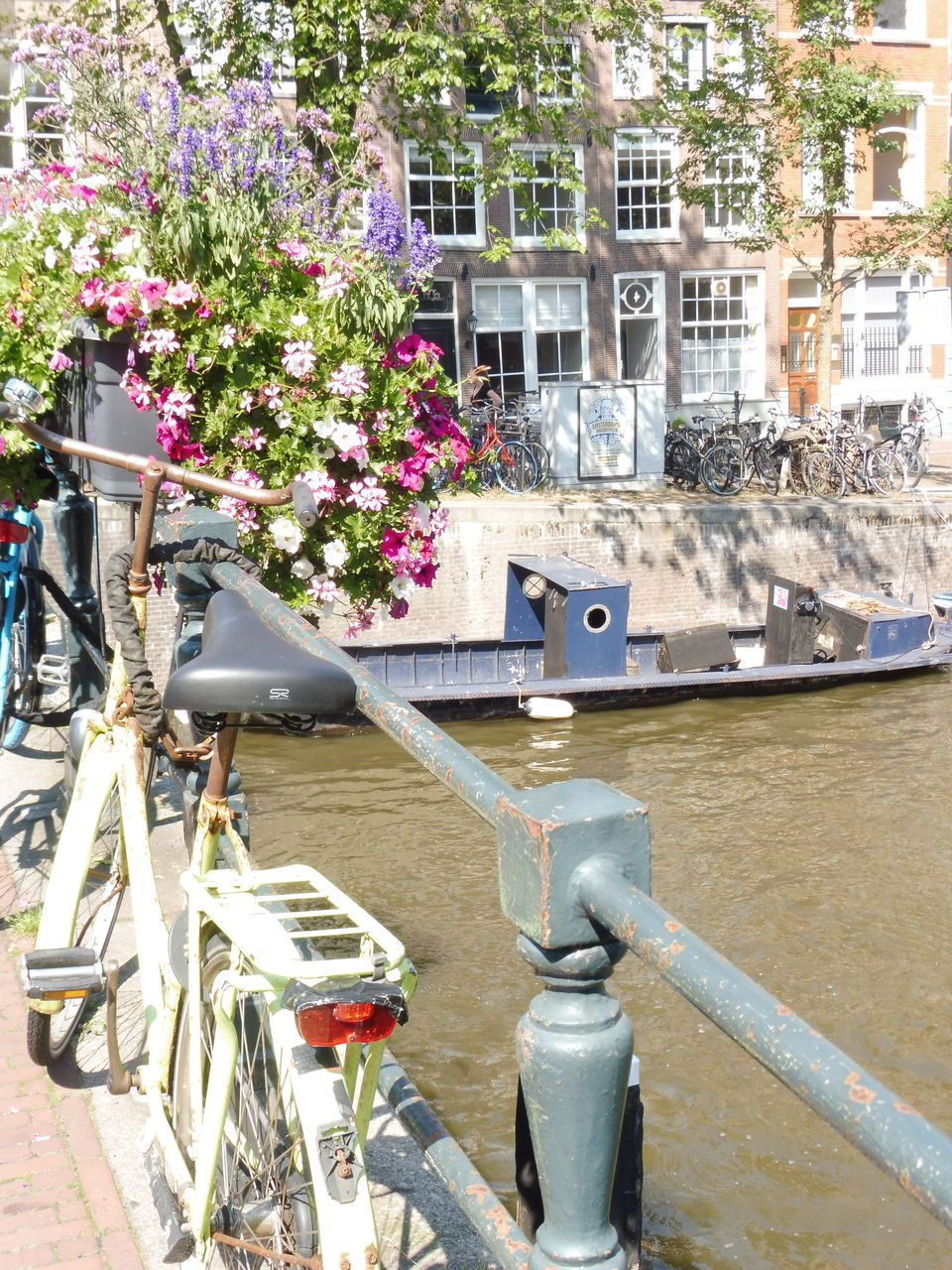 BICYCLE PARKED BY RAILING IN CANAL AGAINST BUILDINGS