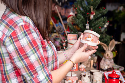 Woman choosing christmas gifts at small craft pottery store. wintertime holidays mood in tropic