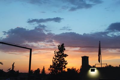 Silhouette factory against sky during sunset