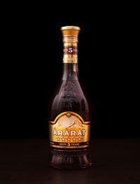 Close-up of glass bottle on table against black background