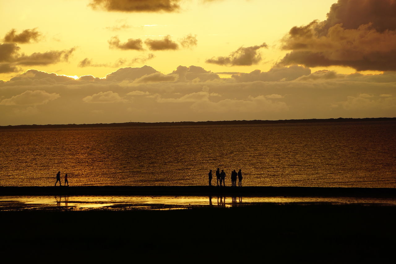 SILHOUETTE PEOPLE AT SEA AGAINST SKY DURING SUNSET