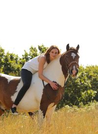 Portrait of young woman with horse on field