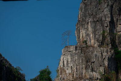 Low angle view of rock formation against clear blue sky