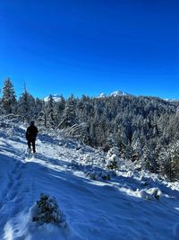 Person on snowcapped mountain against clear blue sky