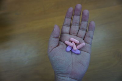 Close-up of person holding pills over table