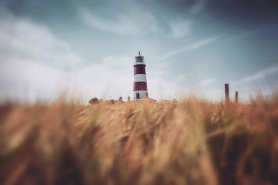 Lighthouse on field against sky