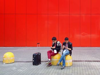 Full length of woman sitting on wall