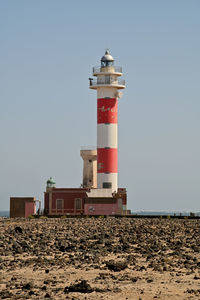 Lighthouse on beach against sky