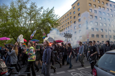 Crowd walking on street by buildings at may day