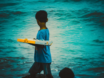 Rear view of boy standing in sea