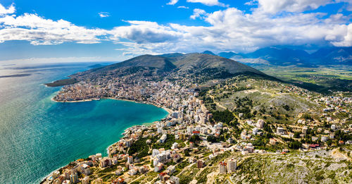 Aerial view of city by sea against sky