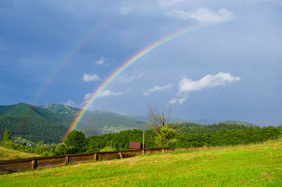 Scenic view of double rainbow over grassy field against sky