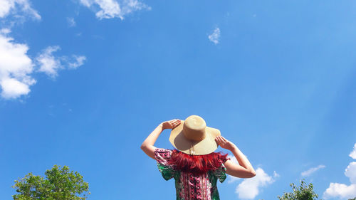 Low angle view of woman standing against blue sky