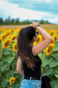 Rear view of woman with arms raised standing against sky