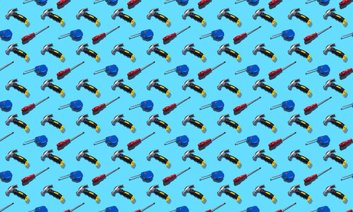 Hammers, screwdrivers and measuring tape on a blue background, pattern, hard shadows.