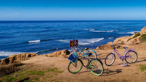 Bicycles on beach by sea against sky