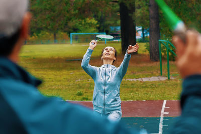 Woman playing badminton with man in park