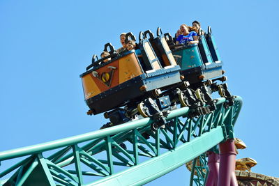 Low angle view of amusement park ride against blue sky