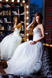 Beautiful bride wearing wedding dress while sitting by mirror