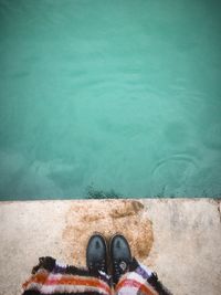 Directly above low section of person standing by sea