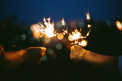 People holding illuminated sparklers at night
