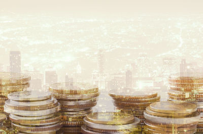 Double exposure of stacked coins and illuminated cityscape